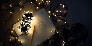 Χριστουγεννιάτικα λαμπάκια διάσπαρτα στο πάτωμα με ένα τετράδιο