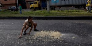 Νεαρός μαζεύει καλαμπόκι που έπεσε από λεηλατημένο φορτηγό στο Πουέρτο Καμπέγιο της Βενεζουέλας