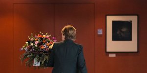 Η καγκελάριος Άνγκελα Μέρκελ με ένα μπουκέτο λουλουδιών αποχωρεί από την αίθουσα