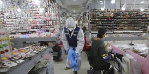 Άνδρας απολυμαίνει τον χώρο σε κατάστημα στην Κίνα λαμβάνοντας μέτρα για τον κορωνοϊό