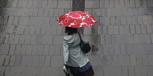 Γυναίκα περπατά σε δρόμο του Σίδνεϊ της Αυστραλίας κρατώντας ομπρέλα για τον βροχερό καιρό