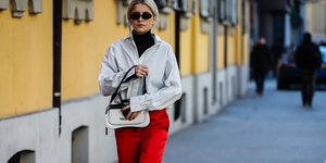 γυναίκα με πουκάμισο και κόκκινο παντελόνι περπατά στο δρόμο