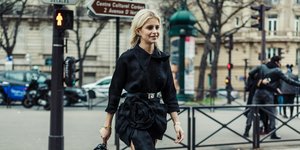 γυναίκα με μαύρο φόρεμα περπατά στον δρόμο