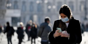 Γυναίκα με μάσκα κοιτά το τηλέφωνο στο Μιλάνο