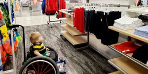 Αγόρι με αμαξίδιο σε μαγαζί με ρούχα