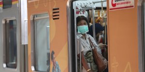 Γυναίκα με ιατρική μάσκα σε συρμό του μετρό στην Ασία