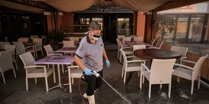 Γυναίκα πλένει πάτωμα εστιατορίου φορώντας ιατρική μάσκα