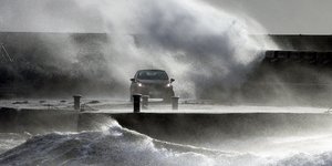 Αυτοκίνητο κινείται σε αποβάθρα ανάμεσα σε μανιασμένα κύματα κατά την καταιγίδα Κιάρα