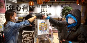 Ανδρας και υπάλληλος σε κατάστημα ανταλλάσσουν τσάντες φορώντας ιατρικές μάσκες