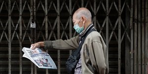 Κινέζος διαβάζει εφημερίδα φορώντας ιατρική μάσκα