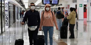 Ταξιδιώτες με βαλίτσες και μάσκες λόγω κορωνοϊού