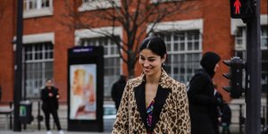 γυναίκα με λεοπάρ παλτό και φόρεμα περπατά στο δρόμο