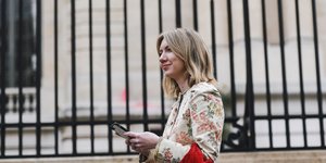 γυναίκα με παλτό και κόκκινη τσάντα περπατά στο δρόμο