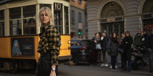 γυναίκα με καρό πανωφόρι περπατά στο δρόμο