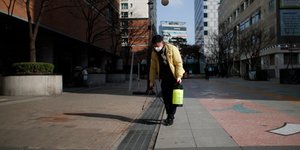 Ανδρας με ιατρική μάσκα απολυμαίνει δρόμο στη Νότια Κορέα