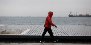 Ανδρας περπατάει με φούτερ στο λιμάνι Θεσσαλονίκης