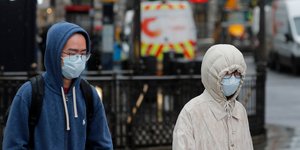 Ανδρες με ιατρικές μάσκες και κουκούλα έξω από μετρό στην Αγγλία