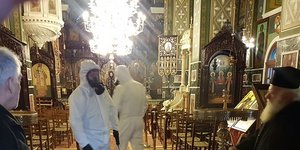 Άνδρες πραγματοποιούν απολύμανση στο εσωτερικό ναού στα πλαίσια εκτάκτων μέτρων ενάντια στον κορωνοϊό