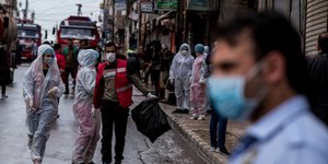 Περαστικοί και εργάτης στη Συρία με μάσκες και ειδικές στολές