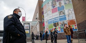 Αστυνομικός με μάσκα έξω από νοσοκομείο στη Νέα Υόρκη και επισκέπτες σε ουρά