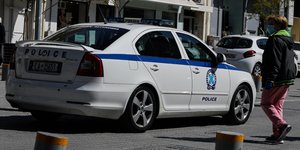 Γυναίκα με μάσκα μπροστά από περιπολικό της ΕΛ.ΑΣ.