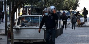 Εργαζόμενος κουβαλά φιάλη με μάσκα