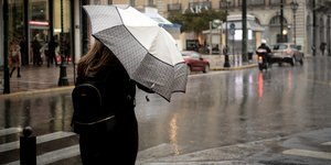 Γυναίκα με ομπρέλα, τσάντα και μαύρο παλτό στην βροχή