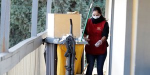 Καθαρίστρια με μάσκα κουβαλάει τρόλεϊ