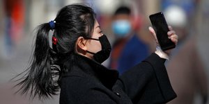 Κινέζα με μαύρη ιατρική μάσκα τραβάει selfie 