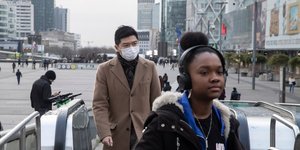 Ανδρας με μάσκα βγαίνει από κυλιόμενες σκάλες