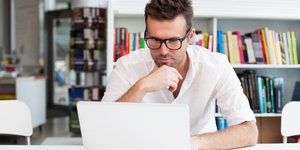 Άνδρας αγγίζει το πρόσωπό του μπροστά σε laptop