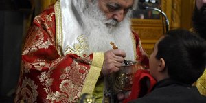 Ιερέας προσφέρει Θεία Κοινωνία σε παιδί