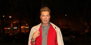 Ο Λάκης Γαβαλάς με κόκκινο σακάκι και μπεζ καμπαρντίνα