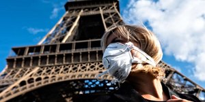 Νεαρή γυναίκα με μάσκα μπροστά στον Πύργο του Αϊφελ/Φωτο GETTY