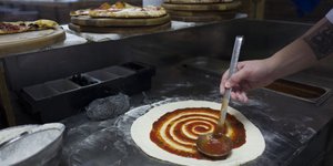 Εικόνα από την κουζίνα πιτσαρίας όπου ετοιμάζεται μια φρέσκια πίτσα