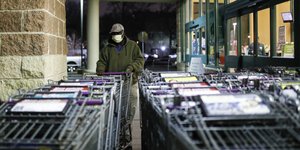 Εργαζόμενος σε σούπερ μάρκετ με μάσκα, μπροστά στα καρότσια