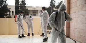 Ανδρες κάνουν απολύμανση σε χώρο στην Συρία