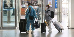 Άφιξη ταξιδιωτών με μάσκες και στολές προστασίας στο σιδηροδρομικό σταθμό της Σεούλ