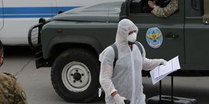 Άνδρας με στολή, γάντια και μάσκα για προστασία ενάντια στον κορωνοϊό