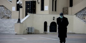 Ηλικιωμένος περνά έξω από εκκλησία με μάσκα