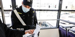 Αστυνομικός με μάσκα πραγματοποιεί ελέγχους για βεβαιώσεις εν μέσω απαγόρευσης κυκλοφορίας