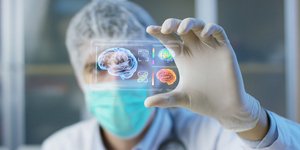 Επιστήμονας με μάσκα και γάντια παρατηρεί το ολόγραμμα ενός εγκεφάλου