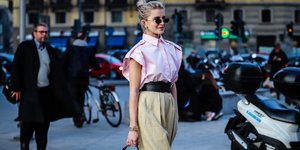 γυναίκα με πουκάμισο και γυαλιά περπατά στο δρόμο