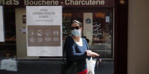 Γυναίκα με μάσκα έξω από κλειστό κατάστημα στη Γαλλία, εξαιτίας των μέτρων περιορισμού για τον κορωνοϊό