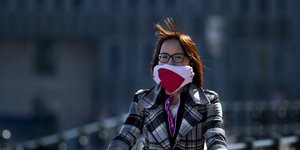 Γυναίκα  με μάσκα κάνει ποδήλατο στο Άμστερνταμ της Ολλανδίας