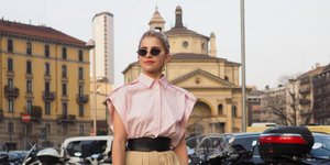 Γυναίκα με ροζ πουκάμισο και μπεζ παντελόνι στο δρόμο 