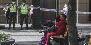 Κόσμος κάθεται σε παγκάκι φορώντας μάσκες