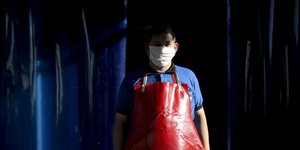 Κρεοπώλης με ποδιά και μάσκα για τον κορωνοϊό σε μαγαζί στην Αργεντινή