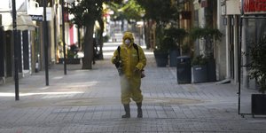 Άνδρας με στολή και μάσκα απολυμαίνει δημόσιο χώρο στην Κύπρο