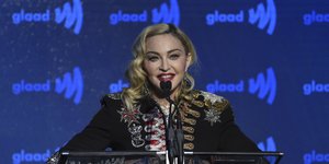 Η Μαντόνα με σακάκι και μπλε φόντο